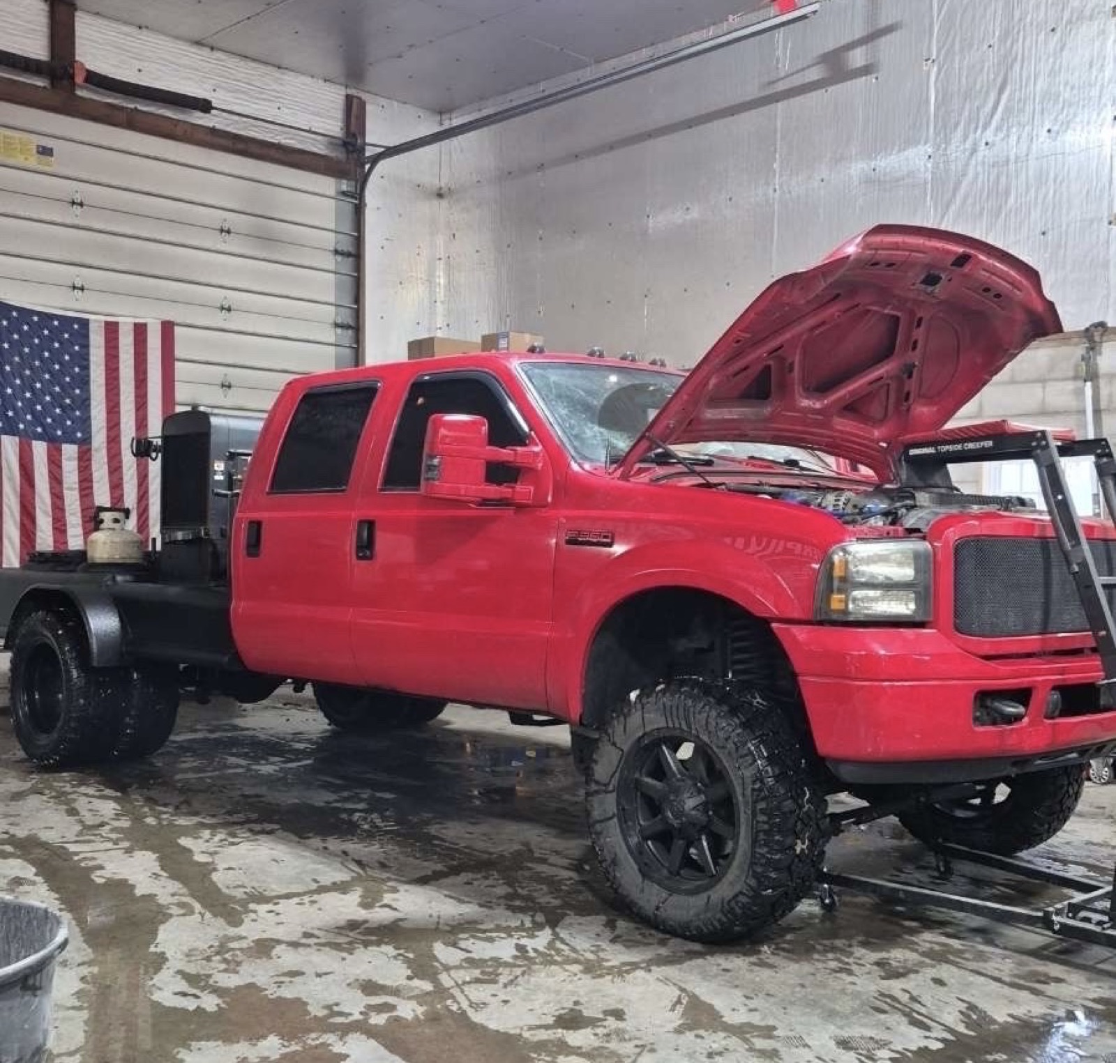 Red Ford F-250 with hood up in the shop